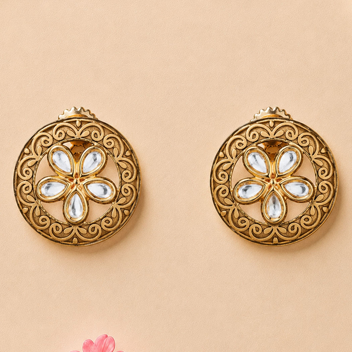 Indian kundan stud earrings in golden tone featuring intricate filigree and clear teardrop stones in floral design