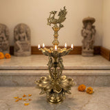 Large peacock brass oil tall diya lamp with intricate lotus design and five lit candles for diwali and home decor