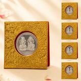 Gold-colored textured box containing a silver-plated laxmi ganesh coin with intricate deity depictions for diwali gift