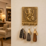 Golden ganesha-themed wall-mounted key holder with ornate detailing and three leather-wrapped keychains for home decor