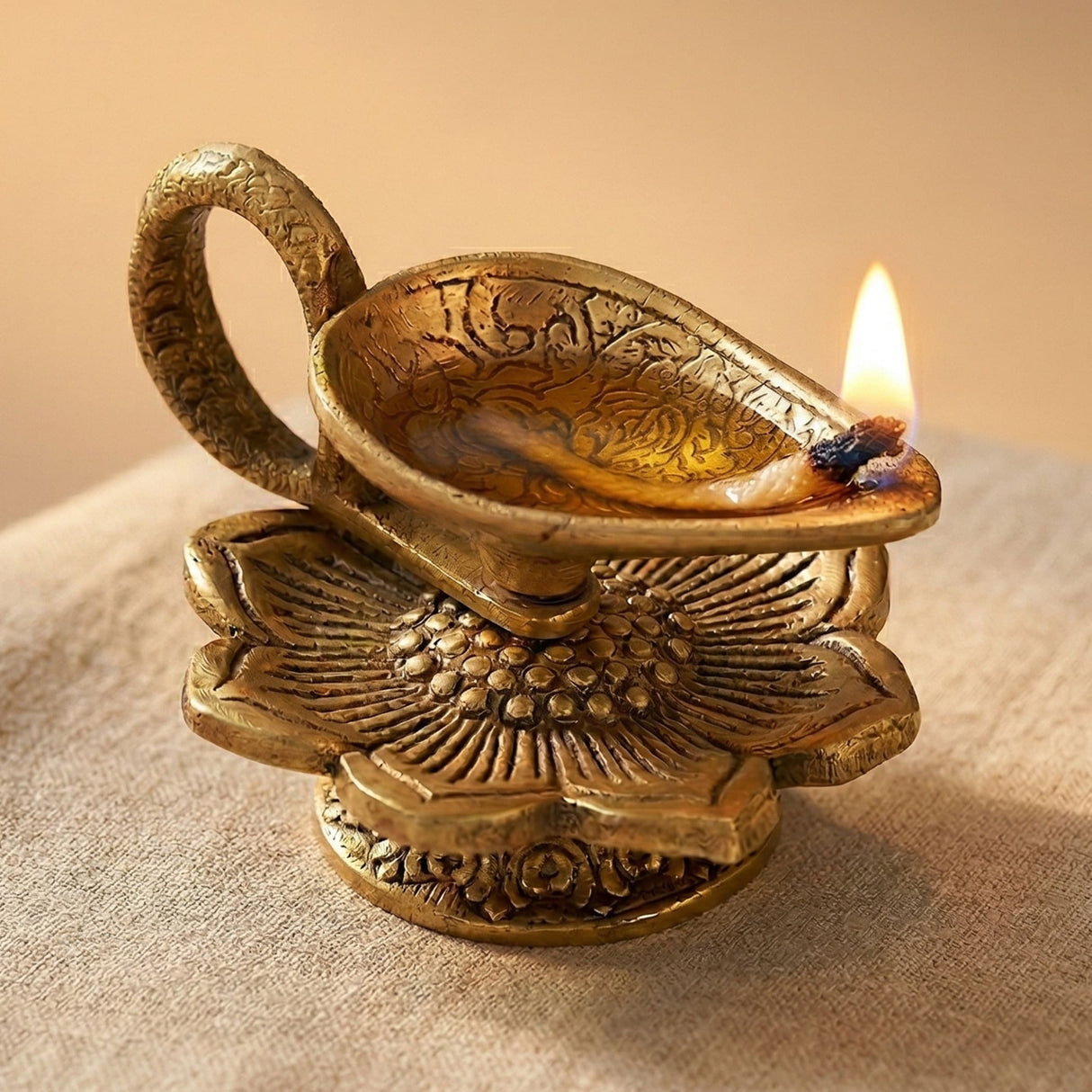 Golden brass oil lamp diya with intricate floral engravings and a lit wick for traditional Hindu pooja and Diwali decor