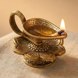 Golden brass oil lamp diya with intricate floral engravings and a lit wick for traditional Hindu pooja and Diwali decor