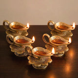 Golden brass lotus finish diya oil lamps with intricate floral engravings and lit candles for home pooja and diwali decor