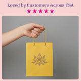 A vibrant yellow lotus paper carry bag with gold rope handles and embossed lotus design for Indian gift occasions