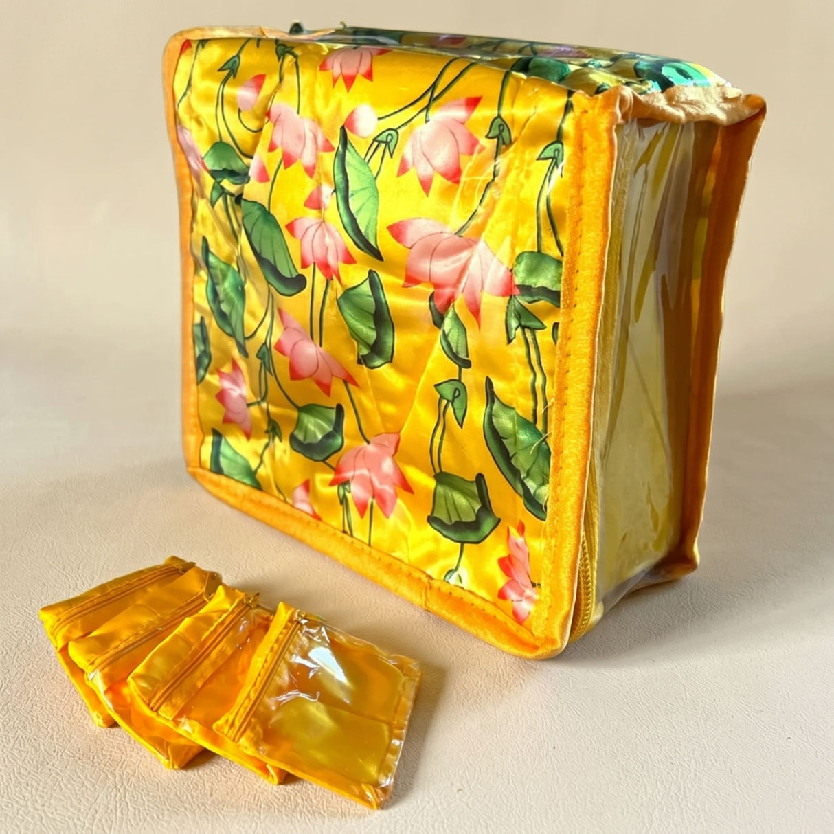 A vibrant yellow satin lotus print Indian jewelry pouch with floral design and golden zippers for travel storage