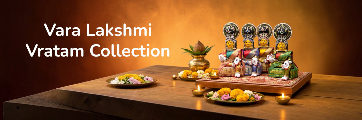 Decorative statues with colorful attire on a wooden platform, surrounded by flowers and candles, with 'Vara Lakshmi Vratam Collection' text.