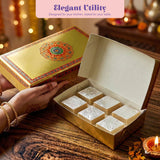 Golden sweet box with intricate orange and green mandala design holding six silver-leafed indian sweets for gifting