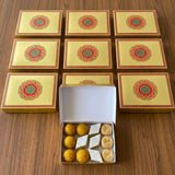 Golden gift box with intricate red and green mandala design open to reveal traditional indian sweets for festive gifting