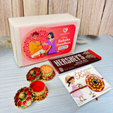 A red and gold floral-design diya with a golden lid filled with vermilion for designer mandala seed rakhi hamper