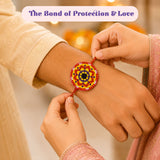 A vibrant designer mandala seed rakhi with red and yellow circular patterns centered on a black dot for brother gift hamper