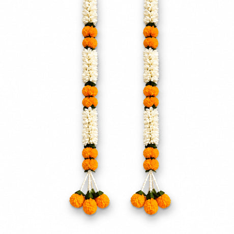 Two vibrant orange and white artificial marigold flower garlands with green leaves and decorative tassels for wedding decor