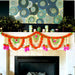 A vibrant orange white and pink artificial marigold jasmine garland with green accents hanging on a fireplace mantel