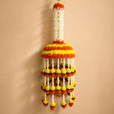 A vibrant orange and yellow marigold string garland with white stems hanging from a green hook for wedding and puja decor
