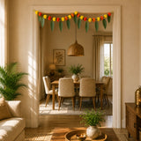 A festive marigold mango leaf door toran hanging valance with yellow orange red pom-poms and green leaf accents for indoor outdoor decor