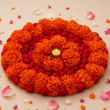 Vibrant orange and red artificial marigold flower rangoli mat with central tea light candle for diwali and pooja decor