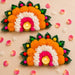 Vibrant orange white and pink marigold rangoli mat with artificial leaves framing two lit tea light candle holders for diwali decor