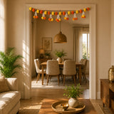 A festive marigold tuberose door toran hanging valance with orange and yellow pom-poms for indoor outdoor decor