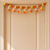 A festive marigold tuberose door toran garland with orange yellow pom-poms and white tassels for indoor outdoor decor