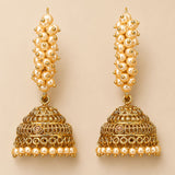Golden jhumka earrings with cream pearl strands and intricate metalwork in gold tone for diwali and ethnic wear