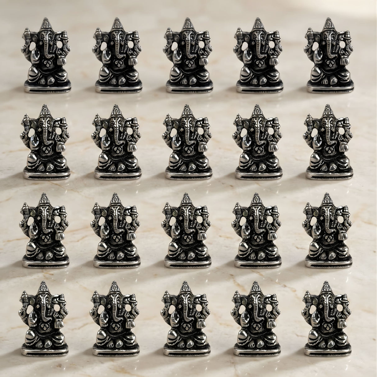 Silver-colored intricately detailed metal ganesha idol figurines arranged in rows for home temple and festival decor