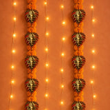 Ornamental ganesha-themed metal leaf wall hanging decor with metallic gold and red accents and marigold pom-poms