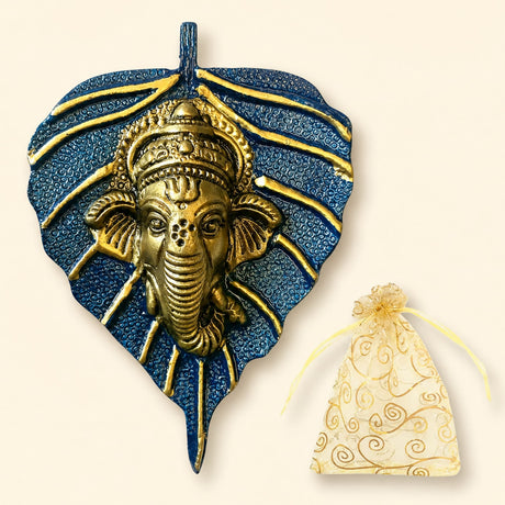 Golden metal leaf ganesha wall hanging decor with intricate detailing on textured blue leaf background for home and office