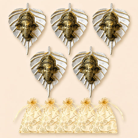 Set of five ornate brass ganesha head wall hangings with silver leaf designs and matching cream organza gift bags