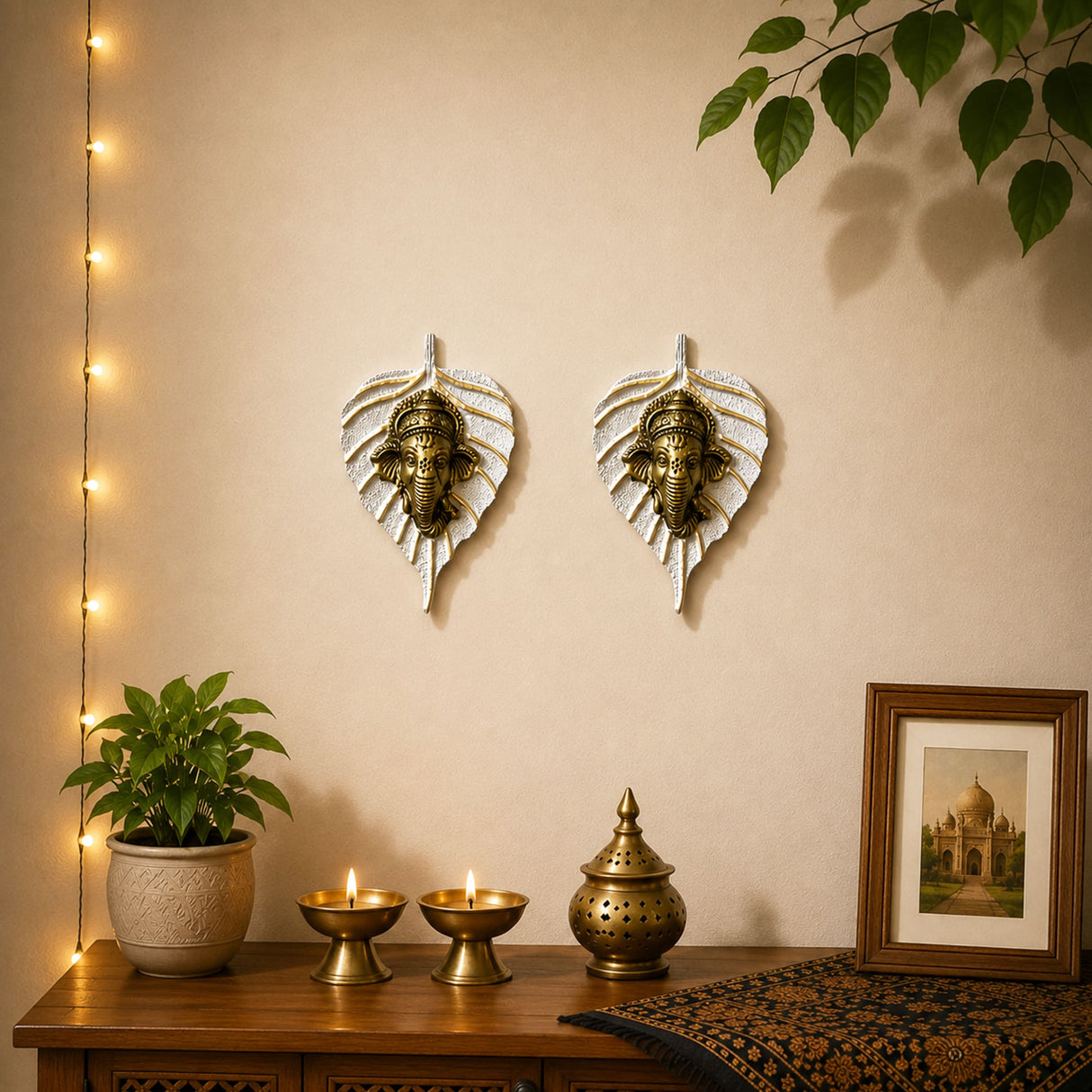 Two golden metal ganesha head wall decor pieces in white leaf-shaped frames for home living room and office decoration