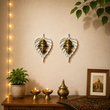 Two golden metal ganesha head wall decor pieces in white leaf-shaped frames for home living room and office decoration