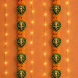 Metal leaf ganesha wall hanging decor featuring golden ganesha head on green leaf backings with orange marigold flowers for diwali and home use