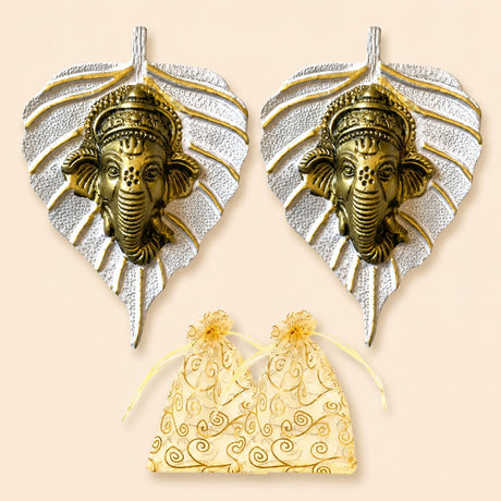 Pair of brass-colored metal leaf ganesha wall hanging decor with silver frames and gold-embossed organza gift bags