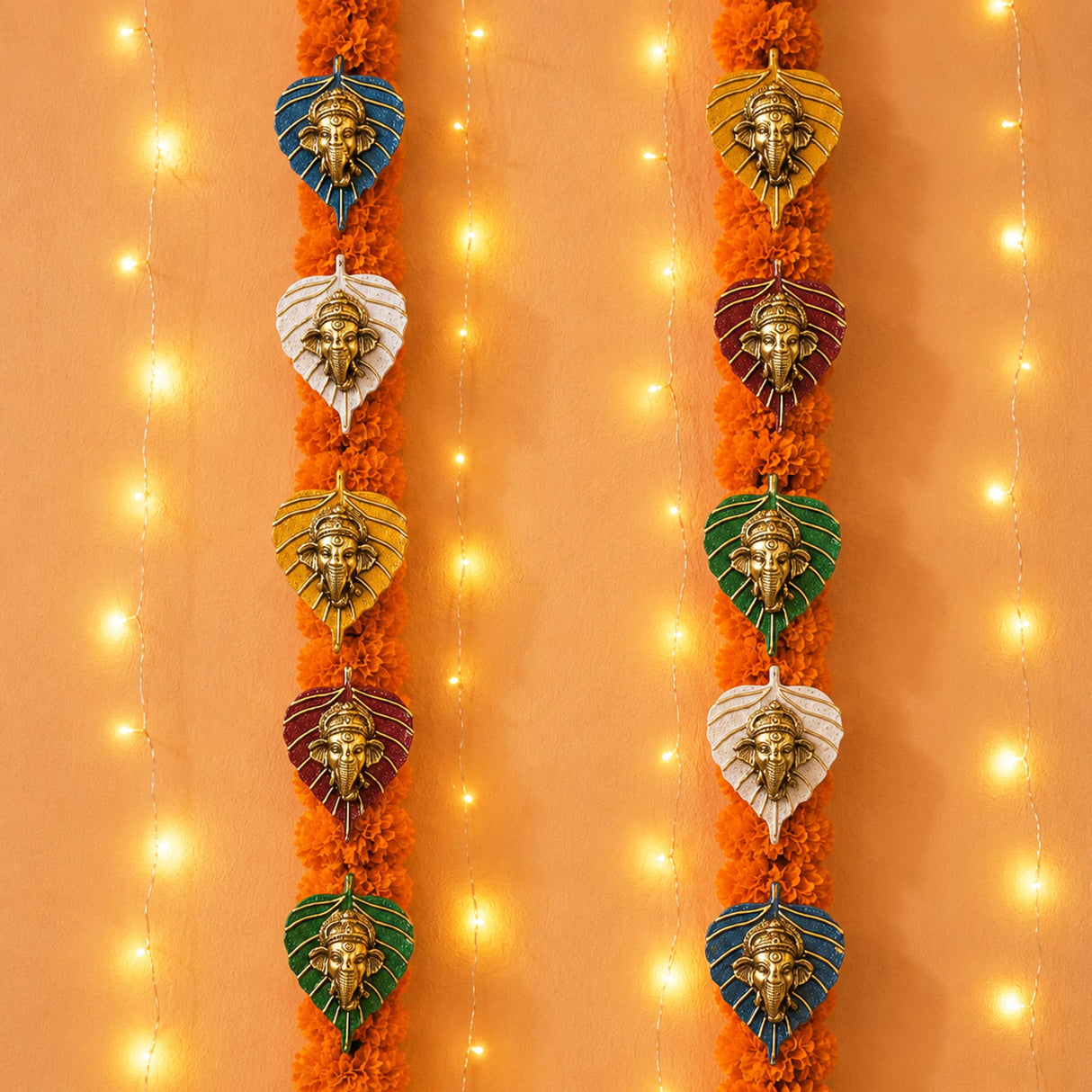 Metal leaf Ganesha wall hanging decor featuring metallic finish head ornaments in leaf-shaped frames with orange marigold garlands