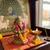 Golden brass 4 inches mini idol ganesha adorned with vibrant pink and orange artificial marigold pooja garland