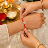 Red cord bracelet with silver om charm in bhai dooj gift hamper symbolizing protection love and good luck