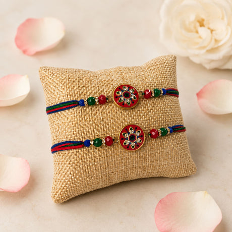 Two handcrafted designer rakhi bracelets in red and blue thread with enamel floral pendants and decorative beads