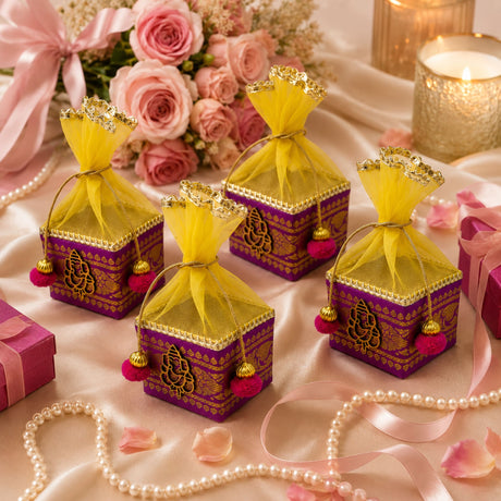 Purple and gold ornate small potli gift boxes with yellow organza drawstrings and pink pom-pom tassels for festive use