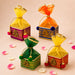Pack of 4 colorful square potli gift boxes with intricate gold embroidery and pom-pom handles for indian wedding favors