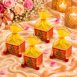 Pack of 4 small red and gold ornate potli gift boxes with yellow sheer organza ties and red tassels for festive gifting