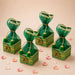 Pack of 4 green and gold ornate potli gift boxes with sheer organza tops tied with golden strings and green pom-poms for indian wedding favors