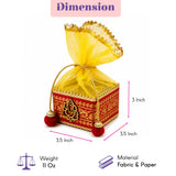 A vibrant red and gold small potli gift box with intricate golden embroidery and yellow sheer organza drawstring top
