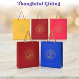 Set of four vibrant eco-friendly om paper carry bags in yellow red pink and blue with gold embossing for Indian gifts