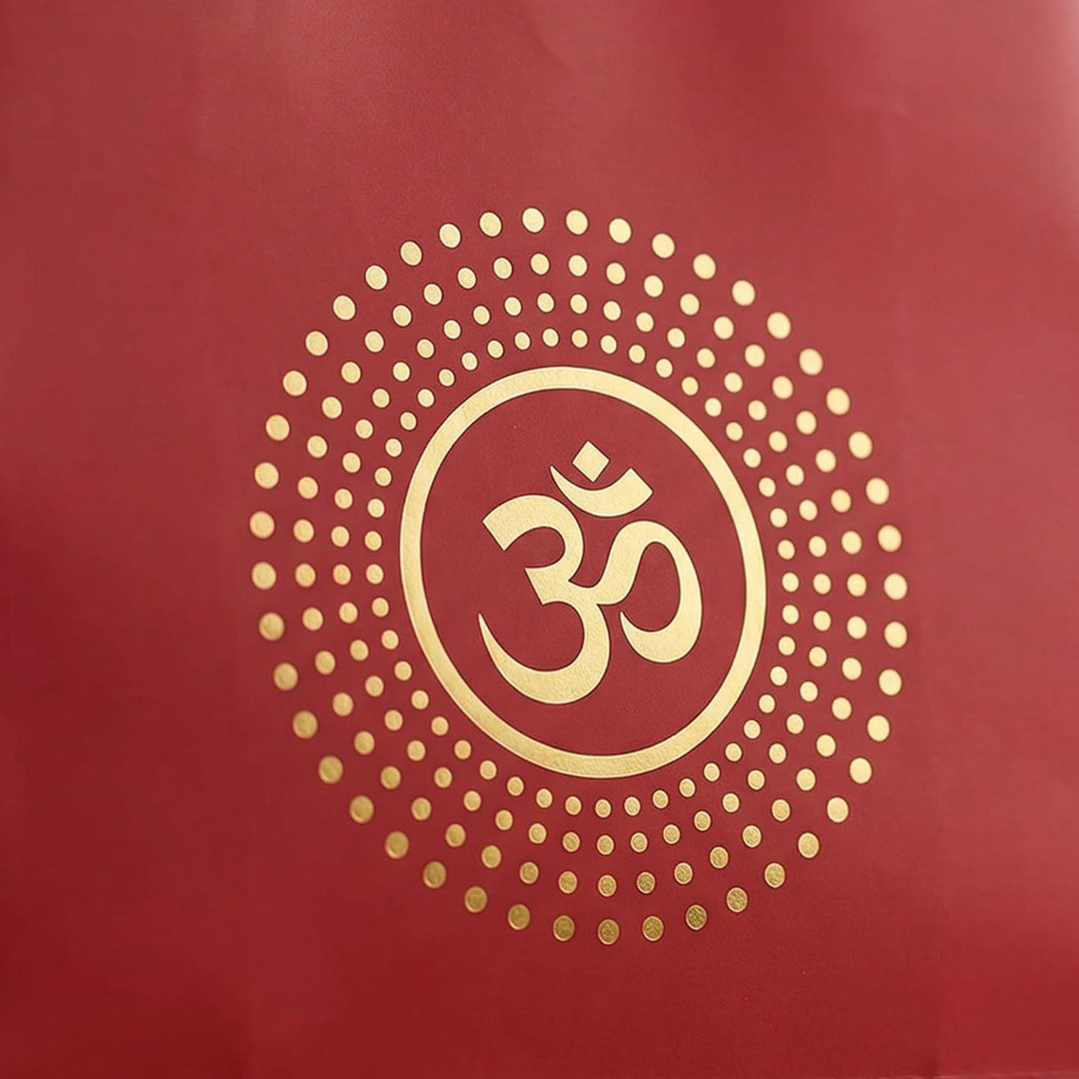 Red eco-friendly paper carry bag featuring a gold om symbol encircled by golden dots for indian festive gifts