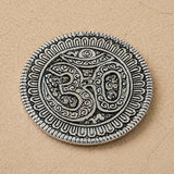 Silver-colored om aluminum incense holder disc with intricate engravings and textured border for temple decor and gifts