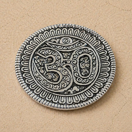 Silver-colored om aluminum incense holder disc with intricate engravings and textured border for temple decor and gifts