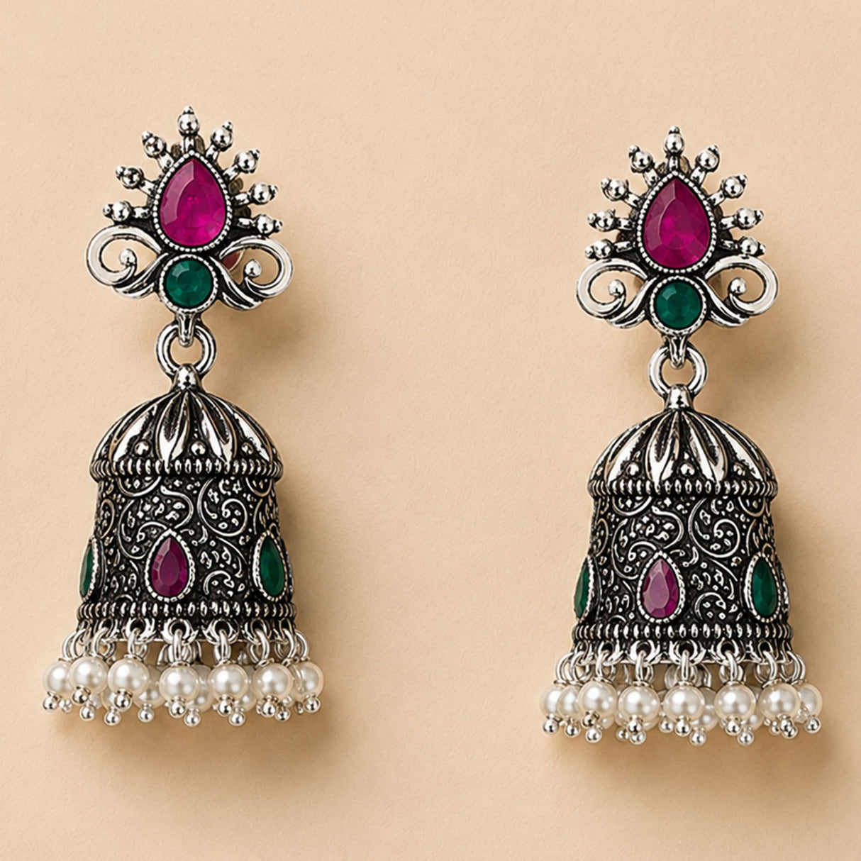 Silver oxidized floral jhumka earrings with intricate filigree, pink and green gemstones, and faux pearl dangles for ethnic wear
