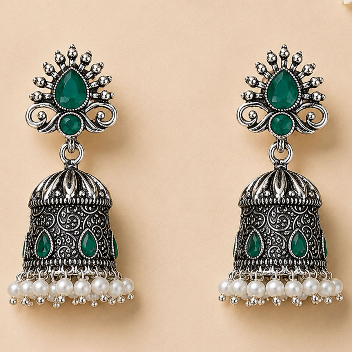 Silver oxidized floral jhumka earrings with intricate filigree emerald stones and white faux pearls for traditional wear