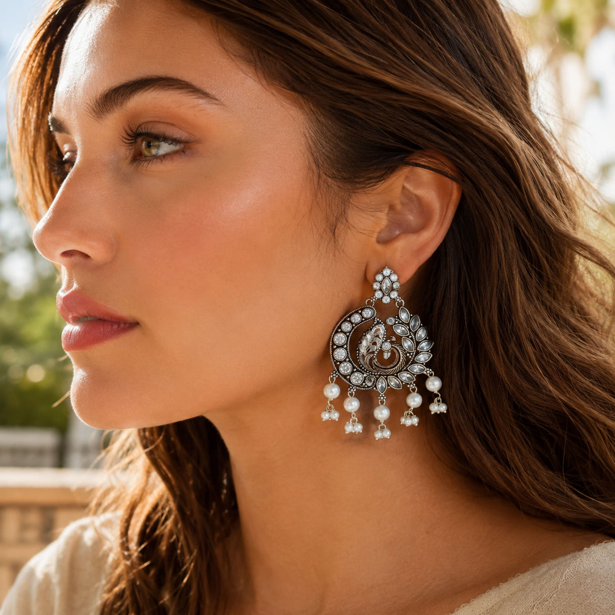 Silver peacock-themed chandbali earrings with clear stones and white pearl dangle for wedding and ethnic wear