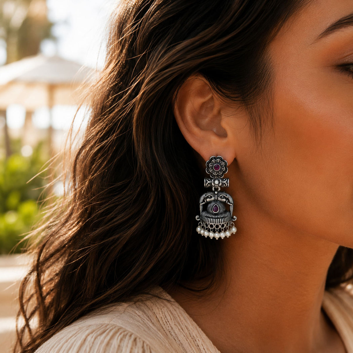 Silver oxidized floral jhumka earring with intricate filigree, central ruby stone, and dangling faux pearl accents for ethnic wear