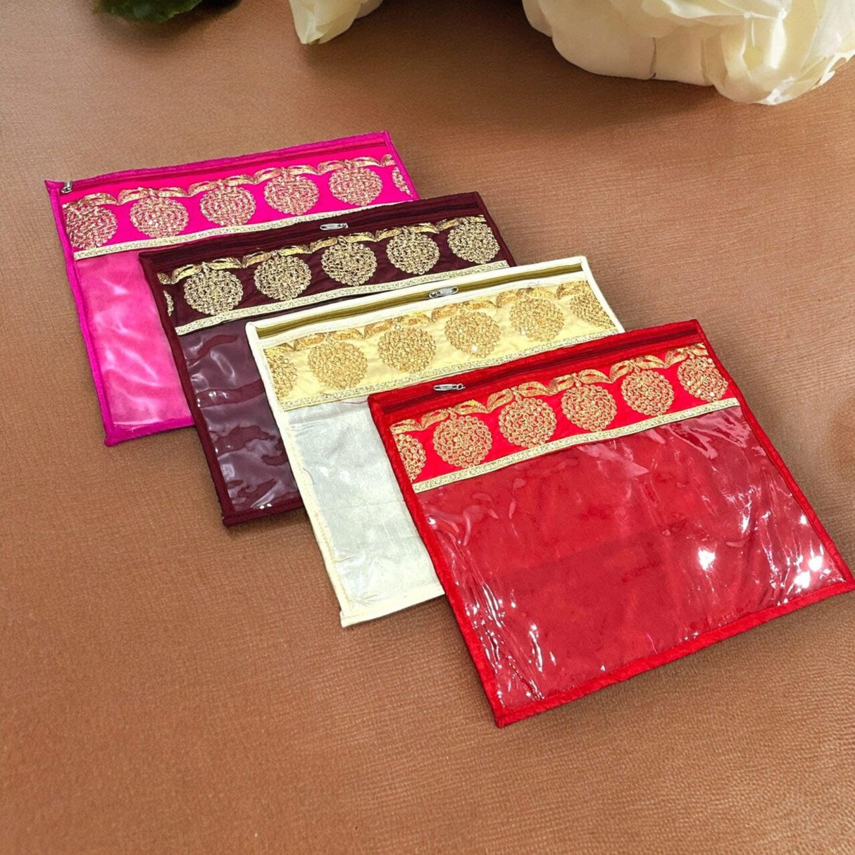 Set of four colorful transparent sari bags with embroidered gold borders in pink maroon cream and red for clothes storage