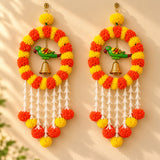 Vibrant orange and yellow artificial marigold pom-pom wreath with green parrot figurine and white tassels for festive decor